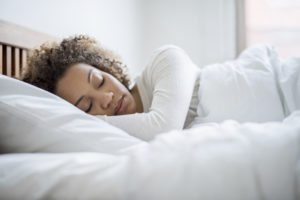 Tired black woman sleeping and looking very comfortable in her bed