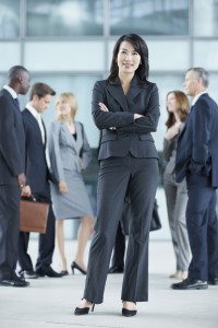 Full-length portrait of a female executive standing in front of her colleagues