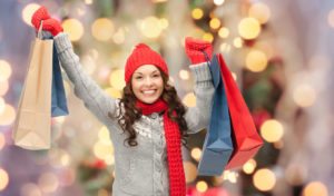 holidays - happy young woman in winter clothes with shopping bags over lights background
