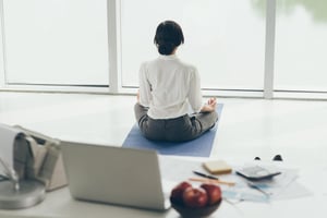 Woman meditating in office looking out window