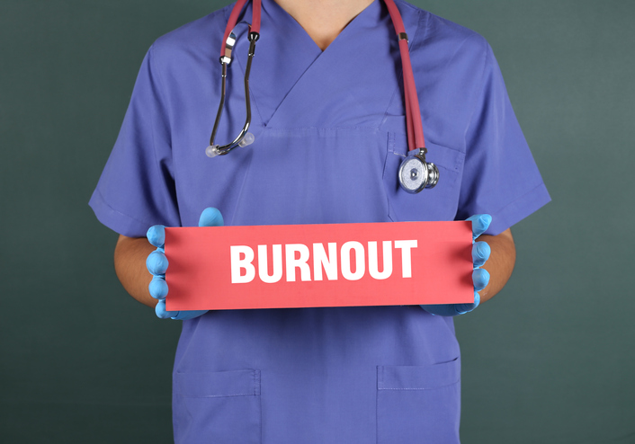 Doctor in scrubs holding red burnout sign_small