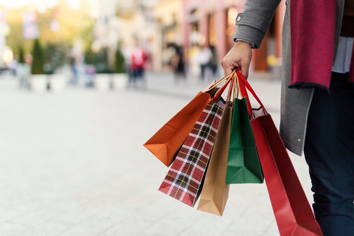 holidays - happy young woman in winter clothes with shopping bags over lights background