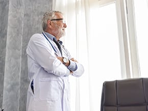 graying physician stares longingly out the window, pondering inquisitively about the winnowing of the labor force