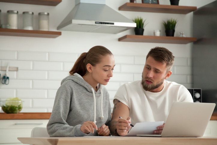Young couple reviewing finances in kitchen
